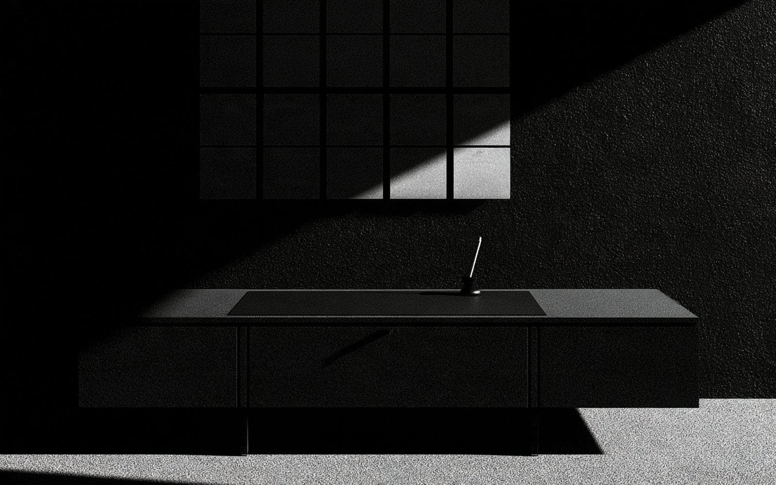 Une diagonale de lumière traverse un intérieur minimaliste et révèle un bureau épuré sous une grille murale, photographie éditoriale sombre en noir et blanc au grain tramé.