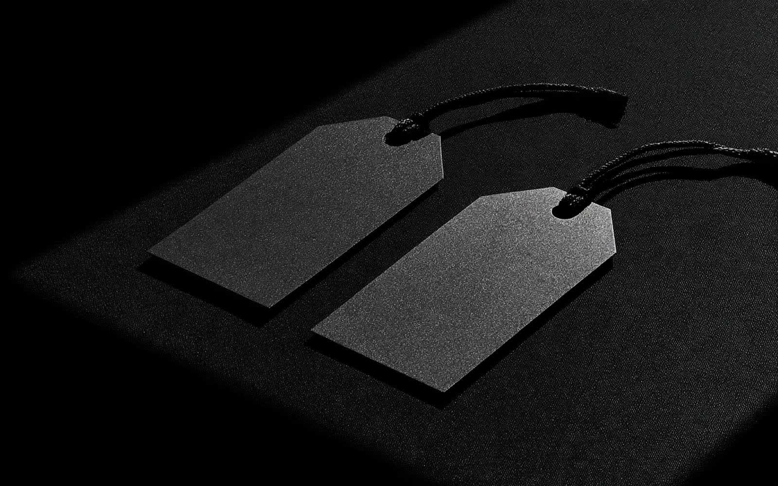 Un smartphone et une étiquette produit posés sur une surface sombre grainée, photographie éditoriale monochrome avec une diagonale de lumière.